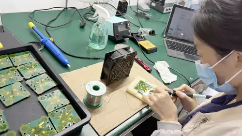 Operator soldering a PCB while following digital work instructions on the factory floor